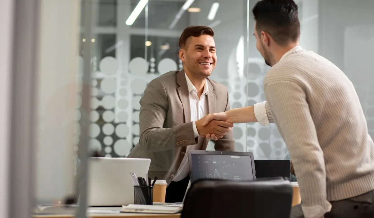 Cliente y consultor sellando un acuerdo con un apretón de manos.